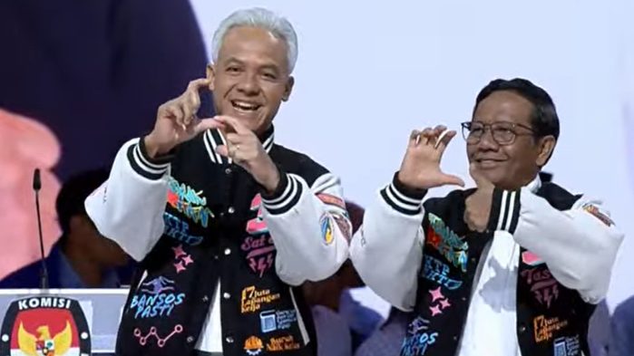Ganjar Pranowo dan Mahfud MD tampil beda di Debat Pilpres Kelima 2024. Mereka menggunakan jaket varsity yang bertuliskan program kerja. (Foto: Tangkapan Layar/Youtube)