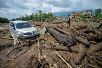 Warga melihat sebuah mobil yang terdampak banjir bandang di Nagari Bukik Batabuah, Agam, Sumatera Barat. (Foto: Antara)