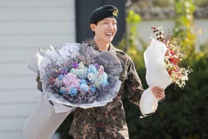 Anggota boy band K-pop BTS, J-Hope, tersenyum sambil memegang bunga setelah dibebastugaskan dari wajib militer selama 18 bulan di luar pangkalan militer di Wonju, Korea Selatan, 17 Oktober 2024. (Foto: REUTERS/Kim Soo-hyeon)